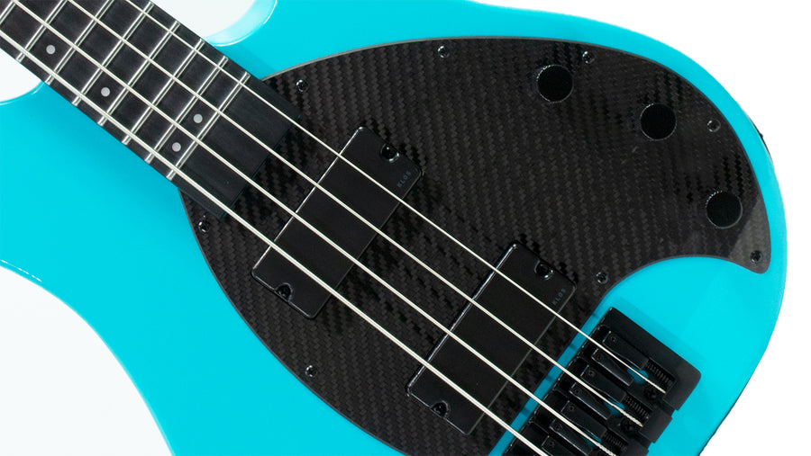 A close up of the carbon fiber pickguard on a aqua pro bass 