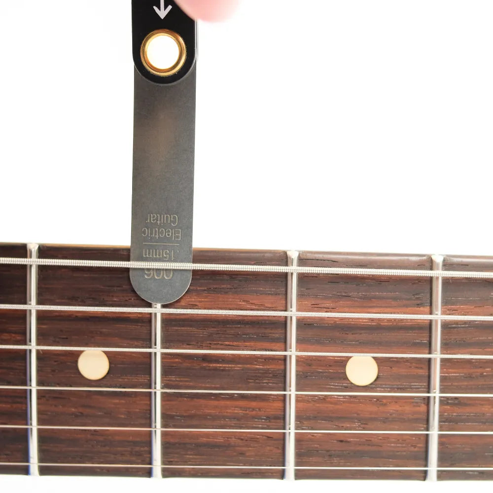 GUITARIST CHECKING NECK RELIEF WITH CAPO AND FEELER GAUGE