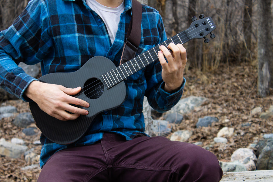 Close up of a tenor ukulele being played in a forest during the fall 